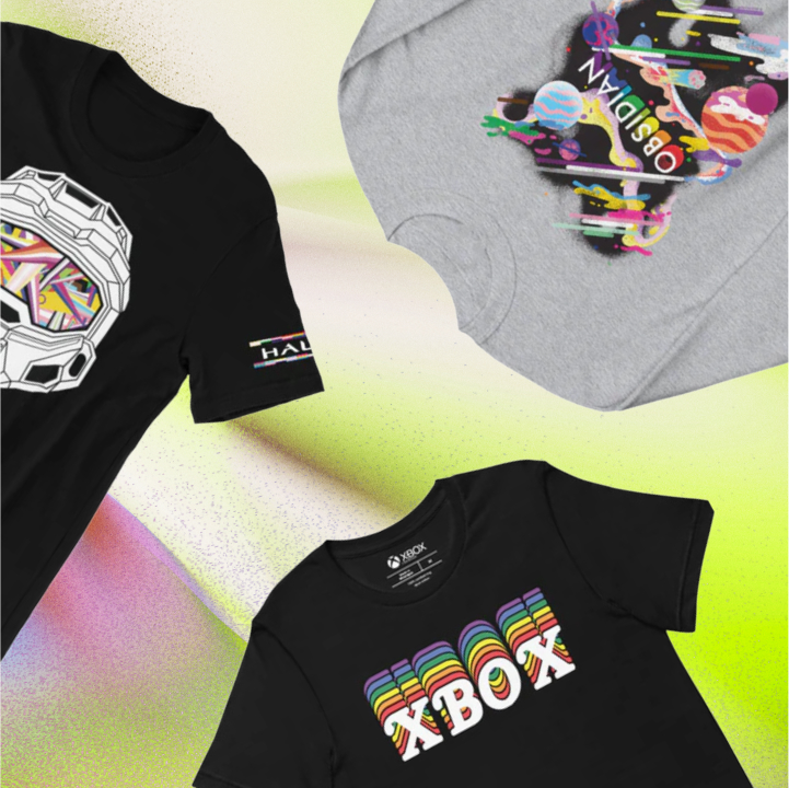 Three graphic t-shirts are displayed on a colorful pastel background. Designs include a Halo helmet, a rainbow-colored Xbox logo, and a shirt with colorful planets and text.